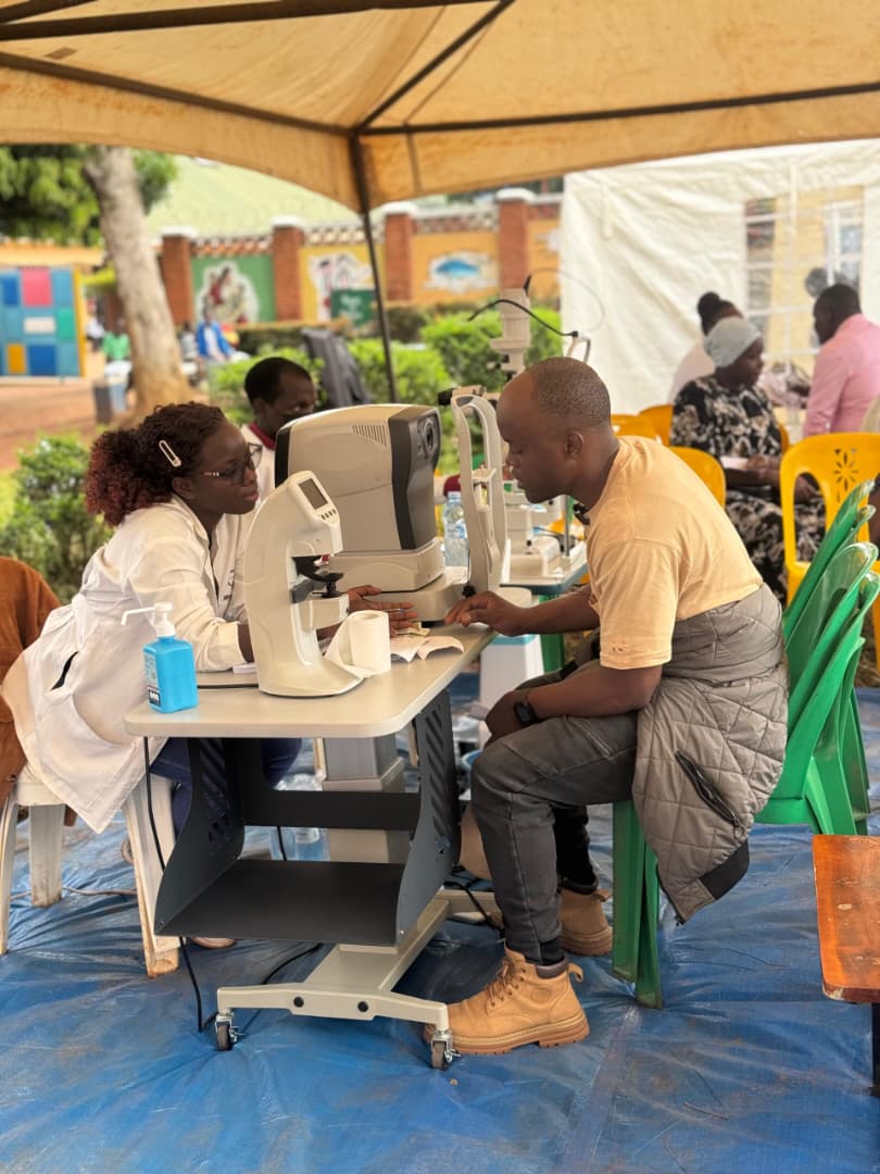 Community members screened at tables under a tent at a village eye camp